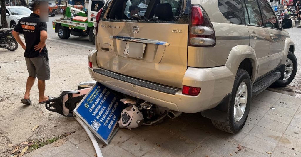 Ô tô Prado lùi trên đường Hà Nội, cuốn xe máy chở 2 phụ nữ vào gầm